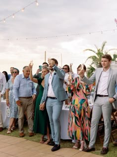 a group of people standing next to each other near a table with food and drinks