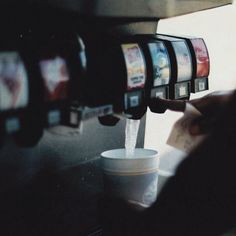 a person filling up a cup from a machine