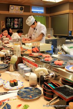 a chef preparing food in a kitchen with many plates and utensils on the counter