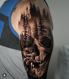 a man's arm with a skull and forest scene on the back of his head