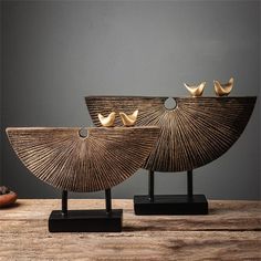 two wooden bowls sitting on top of each other next to a bowl with three birds perched on it