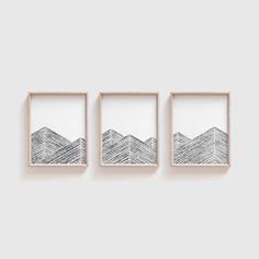 three framed pictures hanging on the wall with mountains drawn in black and white ink above them