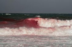 a person riding a surfboard on top of a wave in the ocean with red and white paint