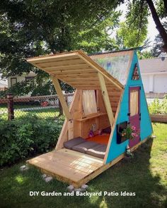 a small house made out of wood and some kind of blue structure in the grass