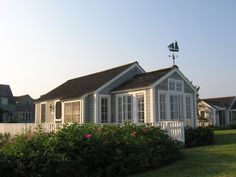 a small white house sitting on top of a lush green field