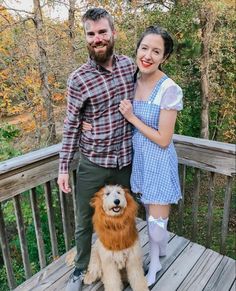 a man and woman standing on a wooden deck with a dog in front of them