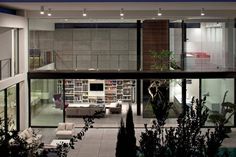 an indoor living area with couches, tables and bookshelves is lit up at night