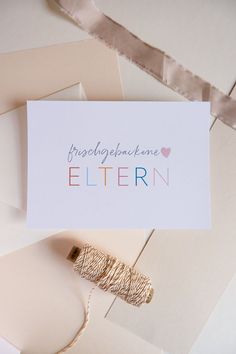 there is a card with the word eltern on it next to twine spools