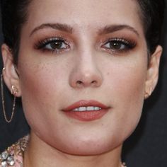 a close up photo of a woman's face with earrings and necklace on her neck