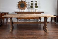 a wooden table sitting on top of a hard wood floor next to two potted plants