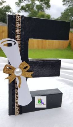 a black and white wooden letter decorated with a bow