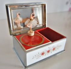 a small box with a doll in it on top of a table next to a mirror