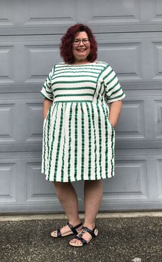 a woman standing in front of a garage door wearing a green and white striped dress