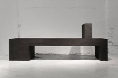 a black and white photo of a bench in the middle of an empty room with concrete walls