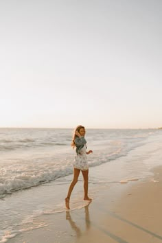 a woman is walking along the beach with her baby