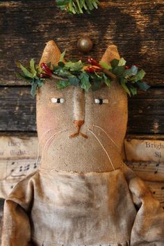 a cat with a wreath on it's head sitting in front of a wooden wall