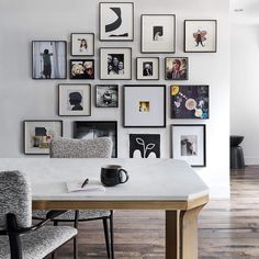 a dining room table with chairs and pictures on the wall above it, along with a coffee mug