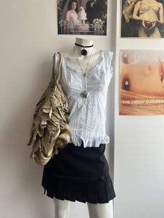 a mannequin wearing a skirt and shirt with pictures on the wall behind it