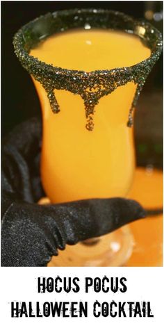 a halloween cocktail in a glass with black gloves on it and the words hoccus pocus halloween cocktail