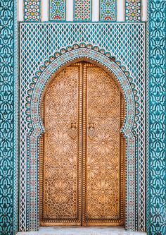 an ornate wooden door in the middle of a building with blue and gold tiles on it