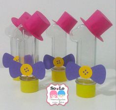 four small vases with different colored paper flowers in them and one has a button on the top