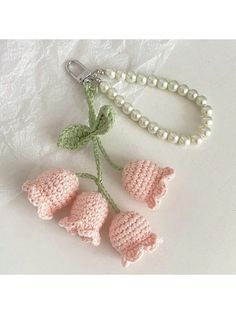 crocheted flowers and pearls are on the table next to a beaded keychain