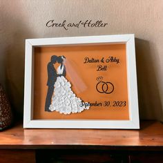 an orange framed wedding photo with the bride and groom holding each other's hands