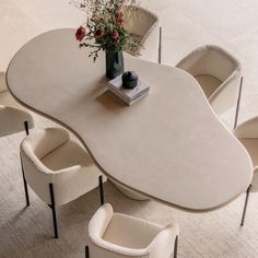 a white table with chairs around it and a vase filled with flowers on the top