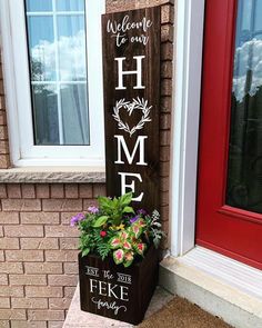 a wooden sign that says welcome to our home with flowers in the planter next to it