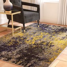 a living room area with a chair, table and rug on the hardwood flooring