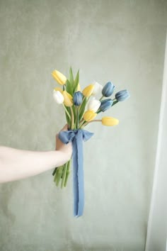 a bouquet of tulips tied to a blue ribbon in someone's hand