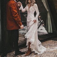 a man and woman standing next to each other in front of a mirror wearing wedding gowns