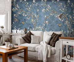 a living room with blue wallpaper and white furniture in the corner, along with a wooden coffee table