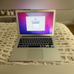 an open laptop computer sitting on top of a bed