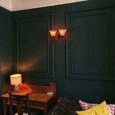 a living room with dark green walls and leather couches in front of a wooden table