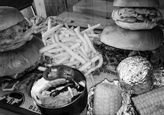 several hamburgers, fries and corn on a table