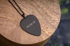 a guitar pick on a wooden table with a chain