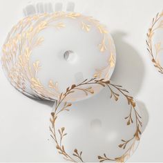 three white plates with gold designs on them sitting next to each other in front of a white background