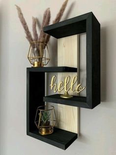 two black shelves with gold letters and some plants on one shelf, while the other is holding an air plant