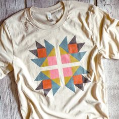 a white t - shirt with an orange, yellow and blue geometric design on it