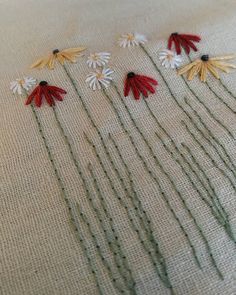 embroidered flowers are arranged in rows on a linen surface