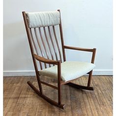 a wooden rocking chair with a white cushion