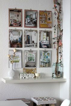 there are many pictures hanging on the wall with magnets attached to it and a tree in front of them