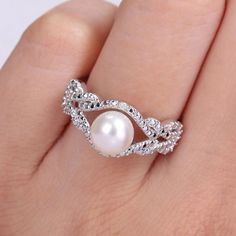 a woman's hand holding a pearl and diamond ring