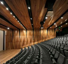 an empty auditorium with wooden walls and black seats