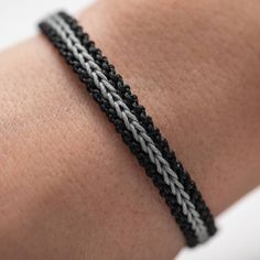 a close up of a person's arm wearing a black and white braid bracelet