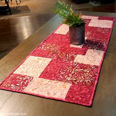 a potted plant sitting on top of a table next to a red and white quilt