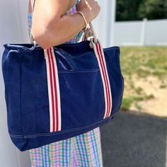 NEW! A rugged, coastal style tote perfect for hauling all your gear to the beach, boat, and beyond. The navy blue canvas with red striped trim is decidedly nautical and chic, and the grommets and leather trim add a refined touch. The natural rope handles are comfortable to carry, and the front pocket and interior zippered pocket keep your belongings safe and organized. 17" x 14". Large enough to carry everything you need throughout the day. Cotton Beach Bag With Braided Handles For Travel, Everyday Canvas Bag With Braided Handles, Navy Casual Canvas Bag With Large Capacity, Canvas Bag With Braided Handles For Everyday Use, Casual Navy Canvas Bag With Large Capacity, Nautical Tote Beach Bag For Travel, Nautical Style Tote Beach Bag For Travel, Nautical Style Beach Tote Bag For Travel, Casual Navy Canvas Tote Bag