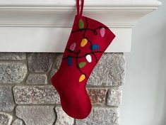 a red christmas stocking hanging from a fireplace