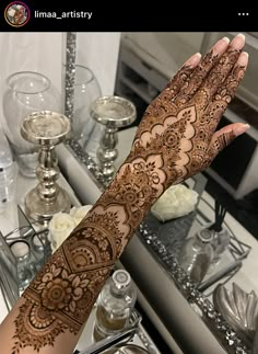 a woman's hand with henna on it and some candles in the background